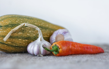 Garlic, red pepper, zucchini. Vegetables on a light background. Autumn harvest. Selective focus. Space for text.