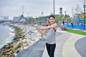 Sports concept. Beautiful girl is exercising on the beach with warm up. Beautiful girl is happy to...