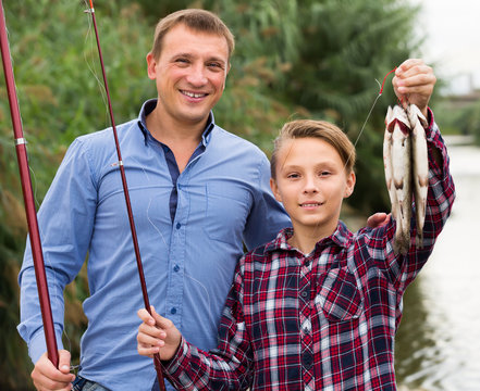 Adult father with son looking at fish on hook