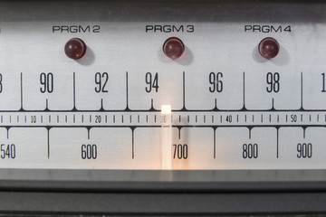 Macro close up of vintage radio tuner dial with lit needle.  