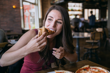 Beautiful model taking a big bite of delicious authentic homemade wood stone oven craft pizza