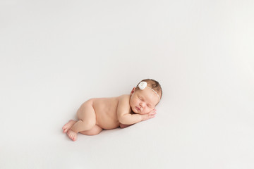 Obraz premium Sleeping newborn girl on a white background. Photoshoot for the newborn. 7 days from birth. A portrait of a beautiful, seven day old, newborn baby girl