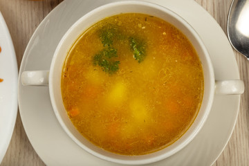 Plate with soup and cutlery on a wooden background.
