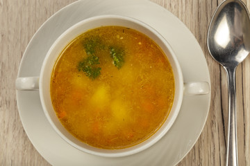 Plate with soup and cutlery on a wooden background.