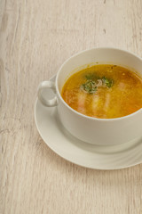 Plate with soup in a white plate on a wooden background.