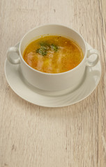 Plate with soup in a white plate on a wooden background.