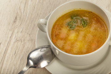 Plate with soup and cutlery on a wooden background.