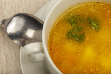 Plate with soup and cutlery on a wooden background.