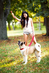 Beautiful woman playing with a dog walking in the park.