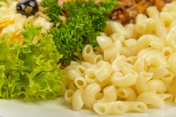 Boiled macaroni on a white plate with fresh herbs.