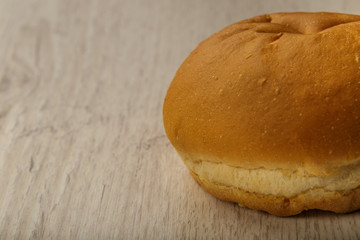 Fresh ruddy bun on a wooden background.