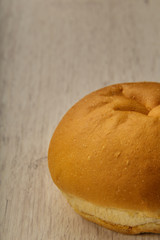 Fresh ruddy bun on a wooden background.