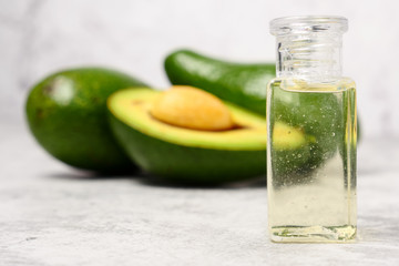 Avocado oil and fresh avocado on cement table.