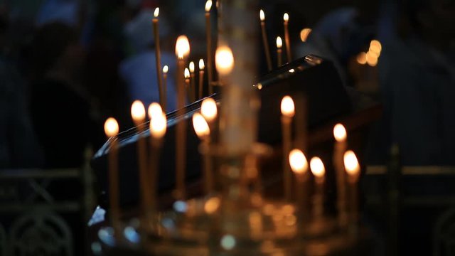 Burning candles in front of the altar in the church. Praying parishioner of the church.