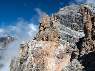 Rock formations on the Tofana di Mezzo peak, blue sky and clouds on the background