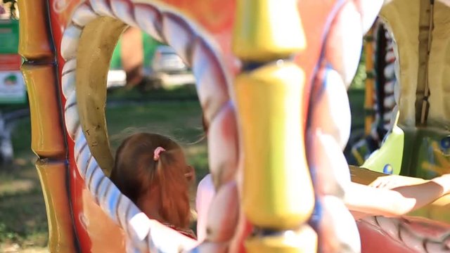 Joyful kids screaming and raising arms while riding roller coaster in amusement park