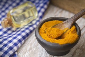 Ground turmeric in a bowl on wooden background- turmeric longa