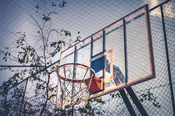 Side and bottom view from a basketball hoop in a daylight. Through this image we can see everything about sports, game, competition, teans, dayoff and much more.