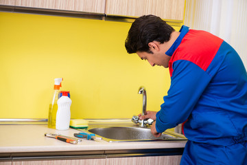 Plumber repairing tap at kitchen