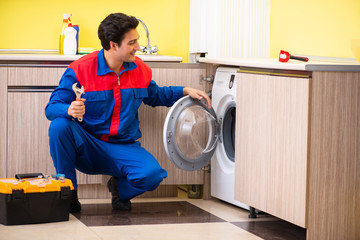 Repairman repairing washing machine in the kitchen