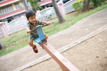 Asian boy playing seesaw and having fun with his mother at kid training playground
