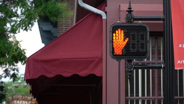 Stop sign of red hand sign at an intersection.