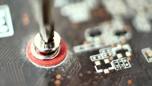 Master in service center for computer repair screw the screw with a screwdriver on circuit board. Concept of computer hardware, repairing, upgrade and technology. Computer repair