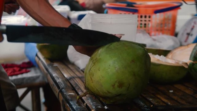 A coconut vendor choose a coconut to open it to make a buko/coconut juice and buko/coconut salad