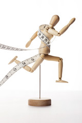 wood Mannequin, human run with tape ruler isolated white.
