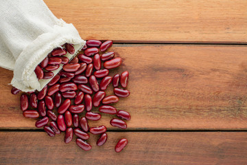 Red beans in sack on wooden table with copy space.
