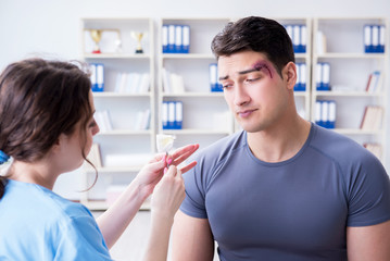 Fototapeta premium Young man visiting female traumatologist with black eye 