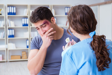 Young man visiting female traumatologist with black eye 