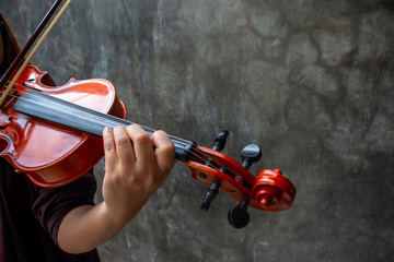Closeup photo of Violinist playing the violin. The classical musician photo with dark background. © AtjananC.