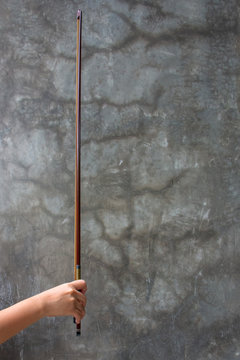 A hand holding a Violin Bow. The close up photo of Violinist holding a violin instrument with the other hand.