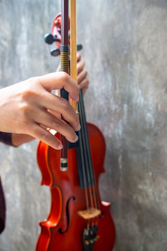 A hand holding a Violin Bow. The close up photo of Violinist holding a violin instrument with the other hand.