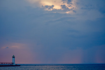 White lighthouse in Michigan on Lake Michigan at sunset with a cloudy pink and blue sky