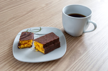 Little chocolate cake and a coffee cup on a wood table