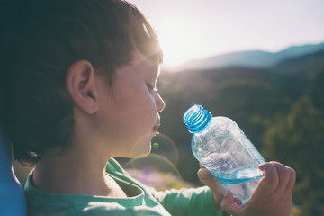 A child drinks water from a bottle.