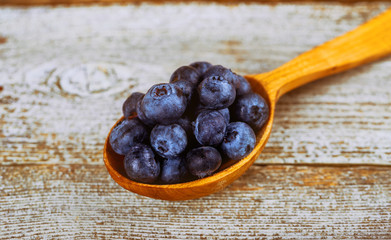 fresh blueberries in wooden spoon over wooden table