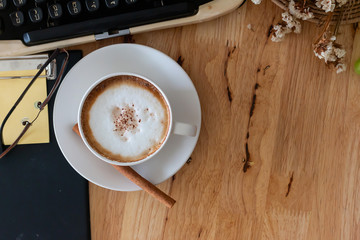 hot coffee in cup and coffee bean and typewriter on the wooden table
