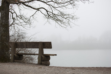Empty bench on the edge of a lake shore in fall symbol for serenity piece quiet and meditation