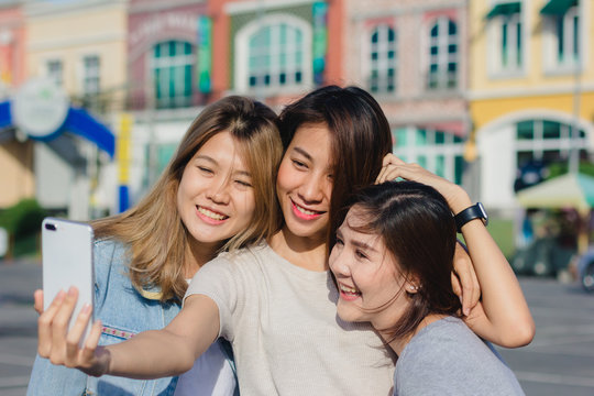 Attractive beautiful asian friends women using a smartphone. Happy young asian teenage at urban city while taking self portraits with her friends together with a smartphone.