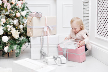 Cute baby and christmas gifts. Little child having fun near Christmas tree in living room. Loving family Merry Christmas and Happy New Year.