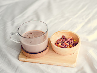 Small snacks set of salted beans and hot chocolate served on the bed.