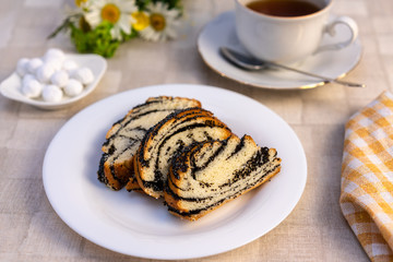 delicious sweet poppy seed cake on a plate, on a table and a Cup of tea