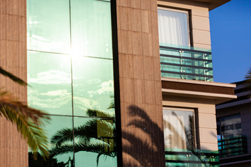 Mirrored facade of modern office building with sunbeams glare reflection