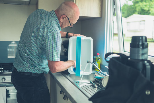 Senior man in caravan cleaning his cooler box