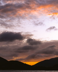 Orange colored cumulus cloud, coastal sunset seascape.