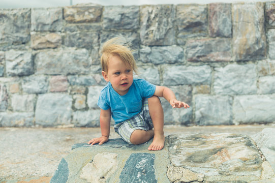 Little toddler by a stone wall