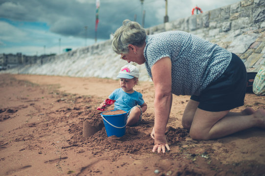 Grandmother helping grandchild build sand castle